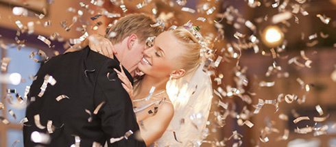 Ein lachendes Brautpaar im Lamettaregen